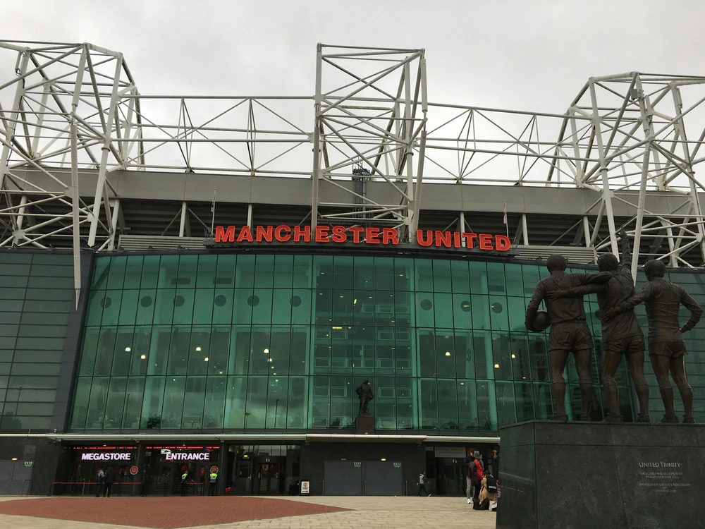 Picture of Old Trafford with the statue of Dennis Law, George Best, and Bobby Charlton