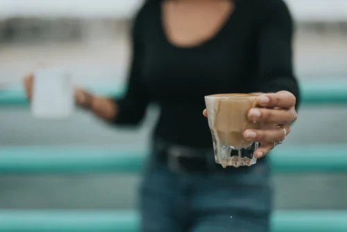 A person handing a cup of coffee to someone