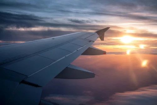 A picture of a plane wing in the air at sunset