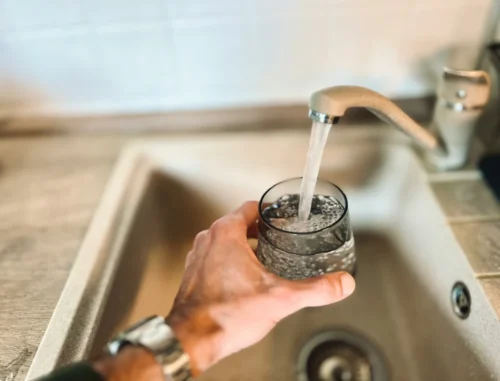 A person pouring a glass of tap water