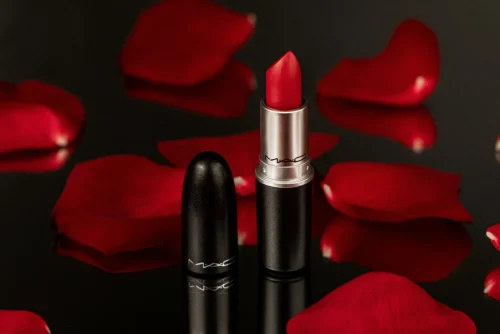Red lipstick with red rose petals in the background