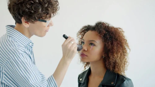 A person using makeup to contour another person's face