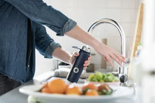 Person filling up reusable bottle with water